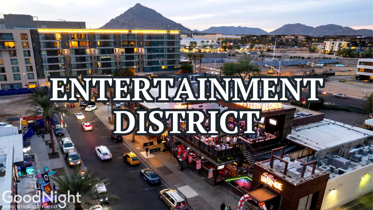 A lively exterior shot of an entertainment venue, with people socializing outside, cars lining the street, and mountains in the background. The scene is energetic, suggesting the dynamic nightlife and entertainment options available nearby.