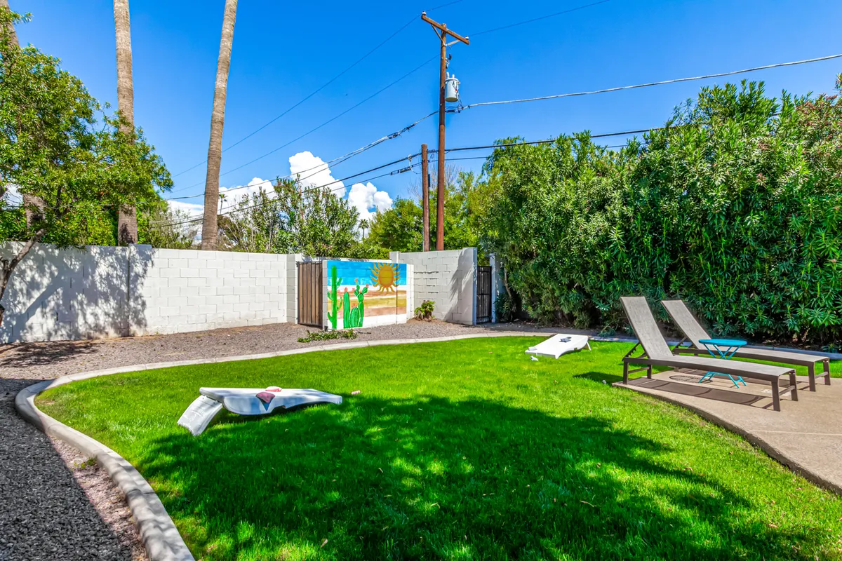 A cheerful outdoor space featuring a green lawn dotted with lounge chairs and a vibrant mural as a backdrop. The open area is well-suited for social gatherings, networking events, or team-building activities under the sun, enhanced by the playful mural that adds character and energy.